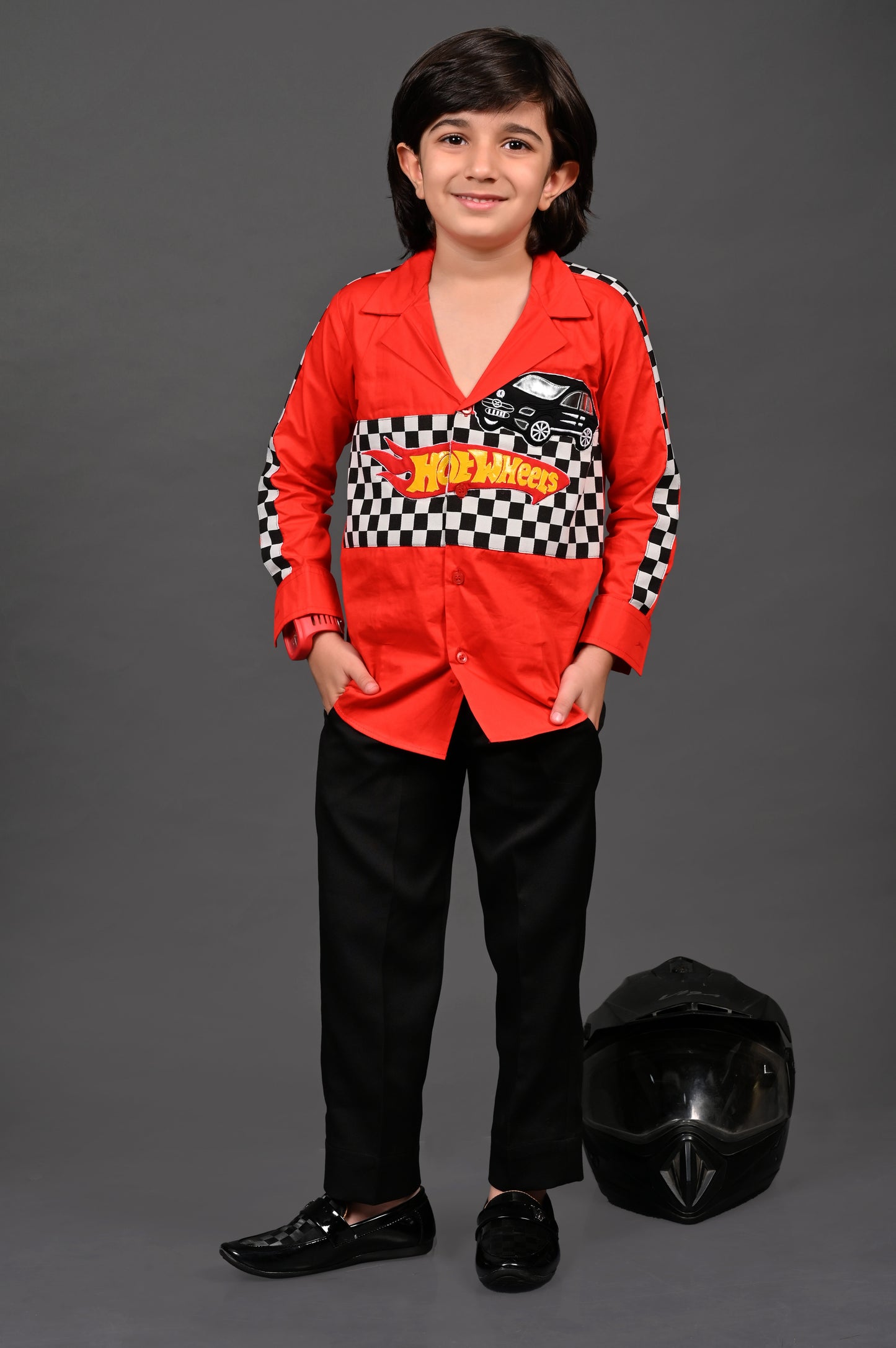 Child wearing a red racing suit with a helmet on a gray background