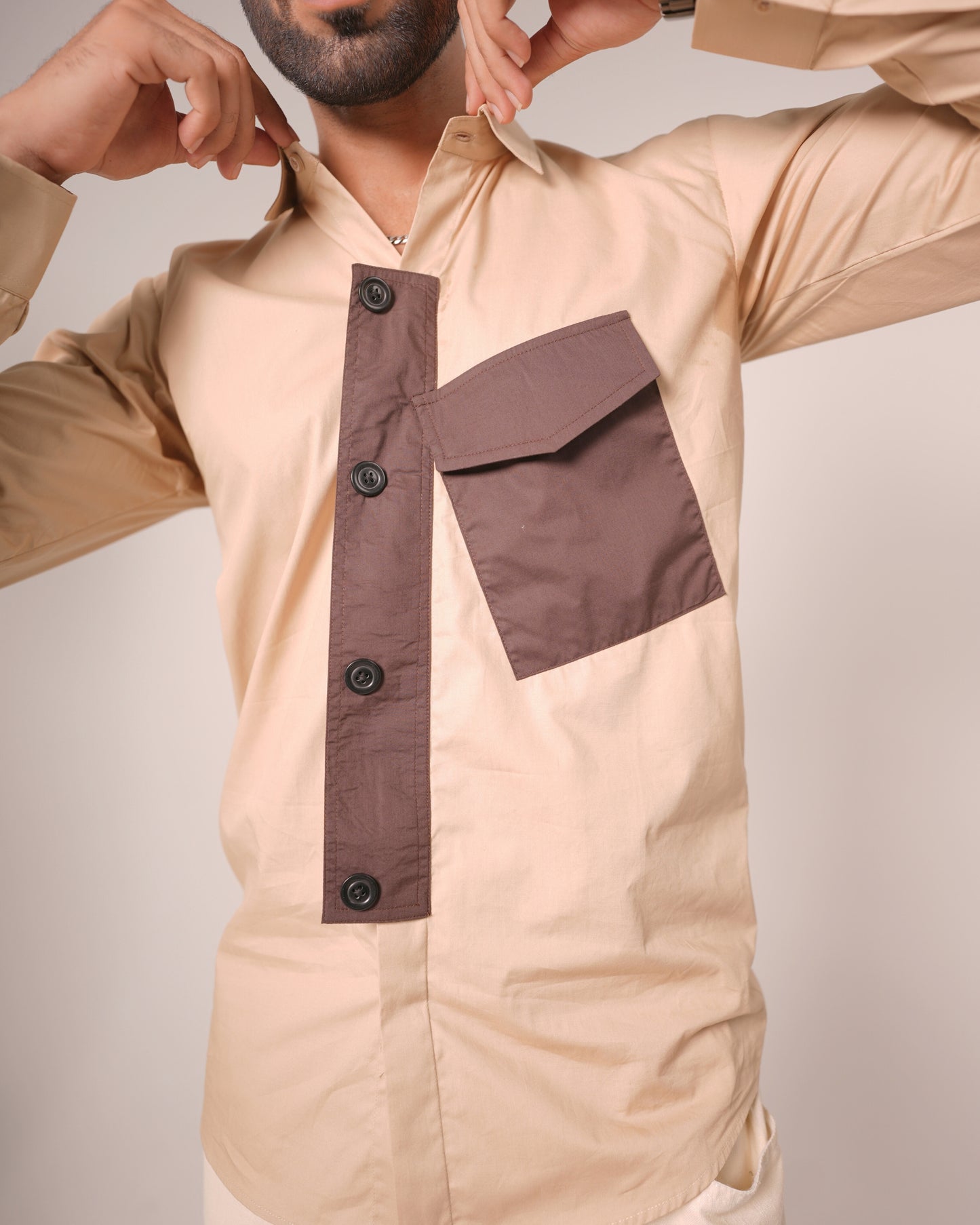 Beige shirt with brown accents worn by a person on a plain background