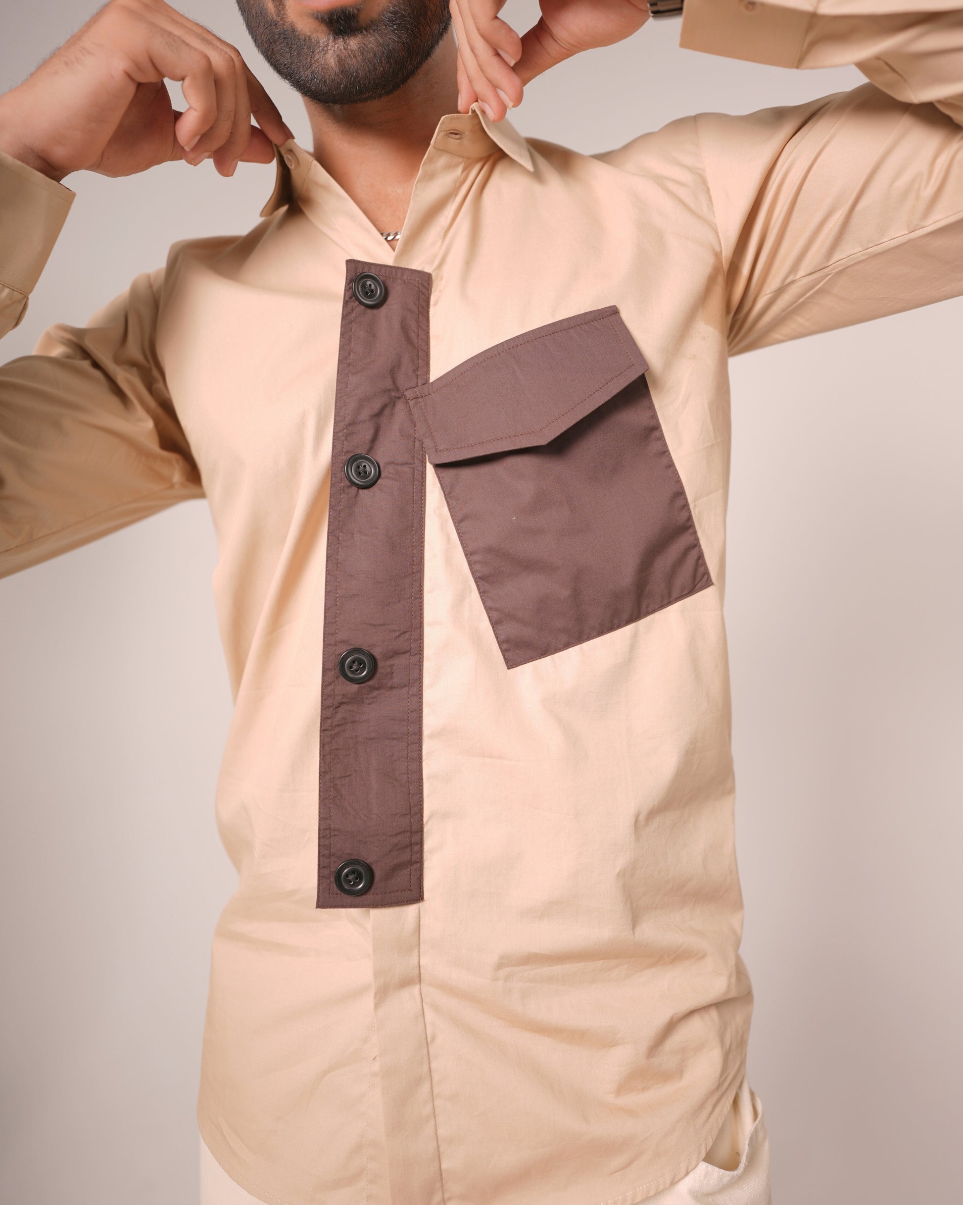 Beige shirt with brown accents worn by a person on a plain background
