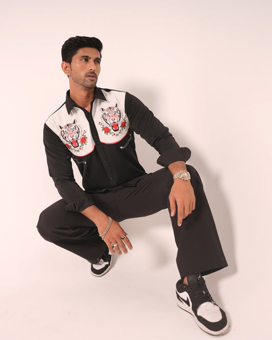 Man wearing a black and white jacket with embroidered designs on a white background
